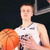 a basketball player with the number 6 on his jersey holds an orange basketball