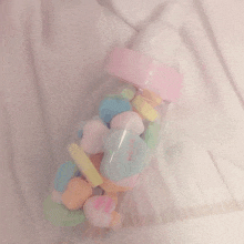 a baby bottle filled with colorful marshmallows on a white background