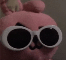 a pink stuffed animal is wearing a pair of white sunglasses .