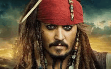 a close up of a man in a pirate costume with dreadlocks and a beard .