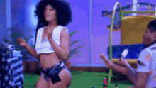 a woman in a crop top and shorts is dancing in front of a man