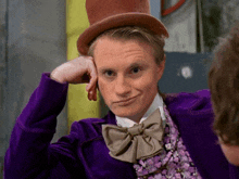 a man wearing a top hat and a purple jacket with a bow tie