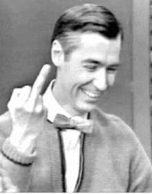 a man wearing a bow tie and a sweater is giving the middle finger