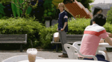 a man in a pink shirt is sitting at a table with a cup of iced tea in front of him .