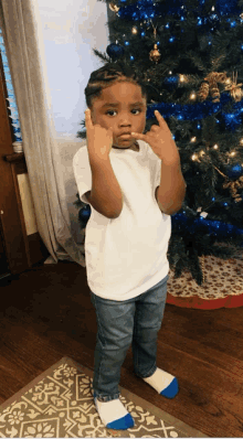 a young boy standing in front of a christmas tree