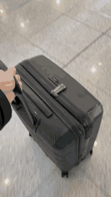 a person is pulling a black suitcase that says ' samsonite ' on the top