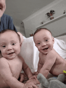 two baby boys are sitting next to each other and smiling for the camera