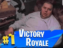 a man is laying on a couch with a sign that says victory royale on it