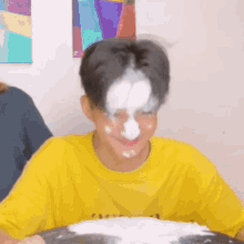 a young boy with white powder on his face is sitting at a table with a plate of food .