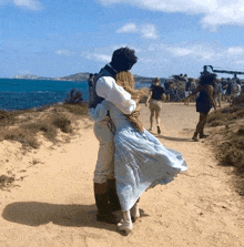 a man and a woman are hugging on a sandy beach near the ocean