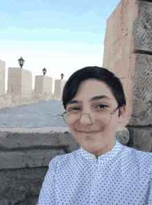 a young boy wearing glasses and a polka dot shirt is smiling for a selfie .