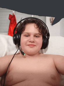 a shirtless boy wearing headphones with a green light on the microphone