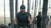 a man with a beard and a helmet walking through a forest