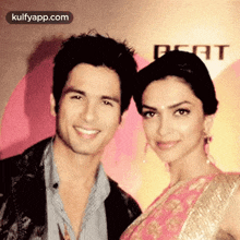 a man and a woman are posing for a picture and the woman is wearing a pink dress .