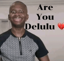 a man is smiling in front of a sign that says " are you delulu "