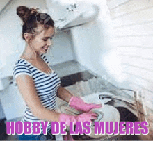 a woman wearing pink gloves is washing dishes in a sink .