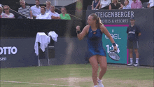 a woman in a blue dress is holding a tennis racquet in front of a steigenberger hotel and resorts sign