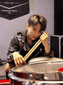 a woman playing drums in front of a handmade cymbals flag