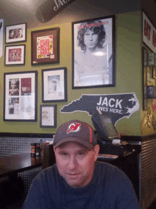 a man sitting in front of a wall with a sign that says jack lives here