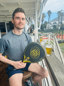 a man sitting on a balcony holding a paddle that says hs on it