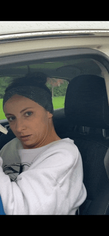 a woman is sitting in the back seat of a car making a funny face