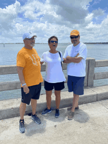 three people standing on a bridge with one wearing an orange shirt that says ' texas ' on it