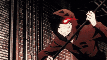 a man in a hoodie is holding a stick with red eyes and a hood .