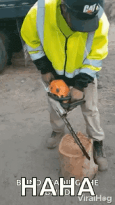 a man in a yellow jacket is using a chainsaw to cut a tree stump .