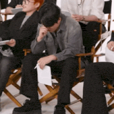 a man sitting in a director 's chair with a piece of paper on his lap