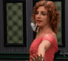 a woman in a pink dress is dancing in front of a wall