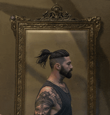 a man with a ponytail and a tattoo on his arm is standing in front of a mirror