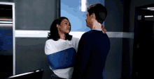 a man and a woman are standing next to each other in a room . the woman is wearing a cast on her arm .