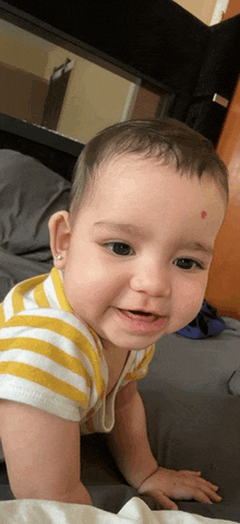 a baby with a red spot on his forehead is smiling for the camera