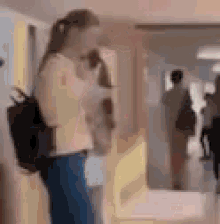 a woman with a backpack is standing in a hallway .