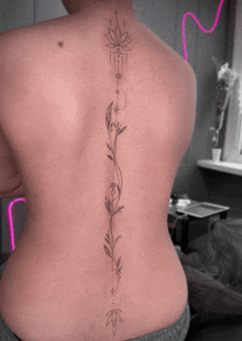 a woman has a tattoo on her back that looks like a flower