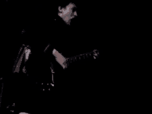 a man is playing a guitar in the dark while singing .