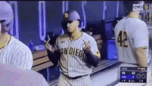 a san diego padres baseball player is giving the middle finger while standing in the dugout during a game .