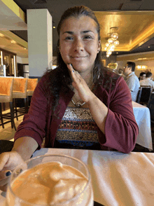 a woman sitting at a table with a glass of milkshake in front of her