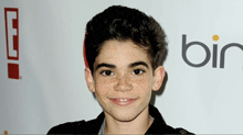 a young boy with freckles is smiling in front of a bin logo