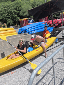 a man and a woman in a yellow kayak with the word kayak on the front