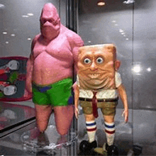 patrick star and spongebob squarepants figurines are standing next to each other on a glass display case .