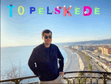 a man stands on a balcony overlooking a city with the word topelskede written in the background