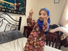 a little girl wearing a floral dress and a blue head scarf giving the middle finger