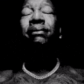 a black and white photo of a man praying with his hands folded in front of his face .