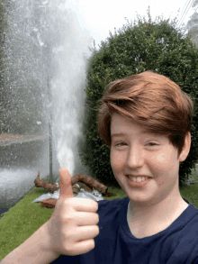 a young boy is giving a thumbs up in front of a water jet