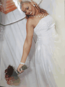 a woman in a white wedding dress is holding a bouquet of red roses