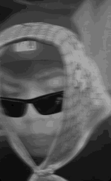 a blurred image of a person wearing sunglasses and a scarf