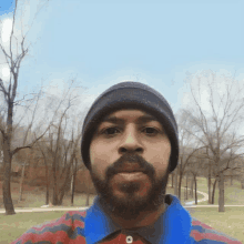 a man with a beard is wearing a beanie and a blue shirt