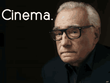 a man wearing glasses stands in front of a black background that says cinema