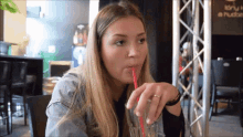 a woman drinks through a red straw in front of a sign that says " i love a place "